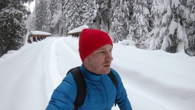 Vlogger在冬季拿着自拍相机雪鞋在桥上行走
