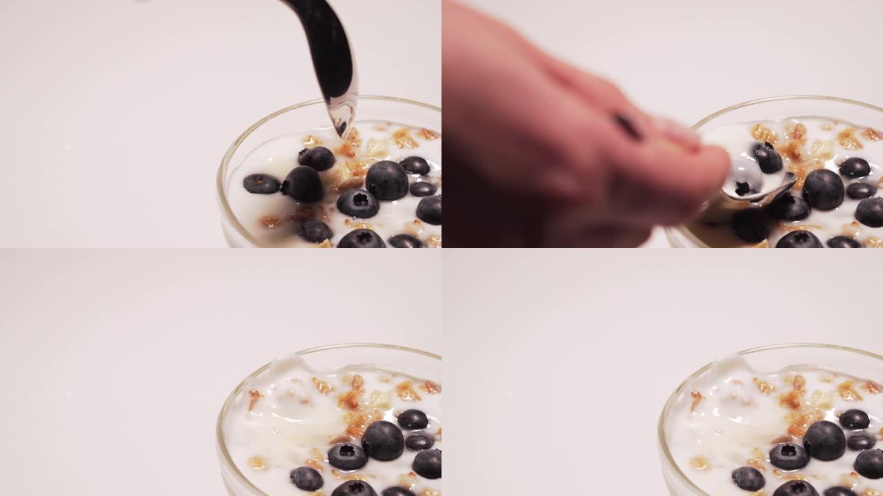 健康格兰诺拉麦片配无麸质酸奶。女孩吃一勺酸奶和一些蓝莓4k