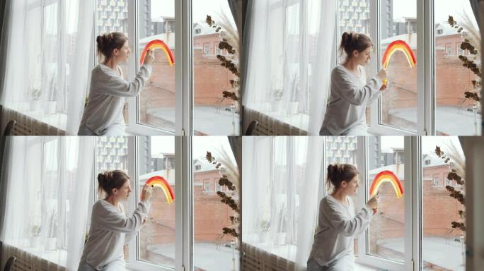 女人呆在隔离的家里，在窗户上画彩虹