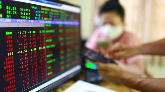 证券交易所市场业务。在智能手机上显示带有模糊红色图形的股票市场报价，患者戴着口罩。