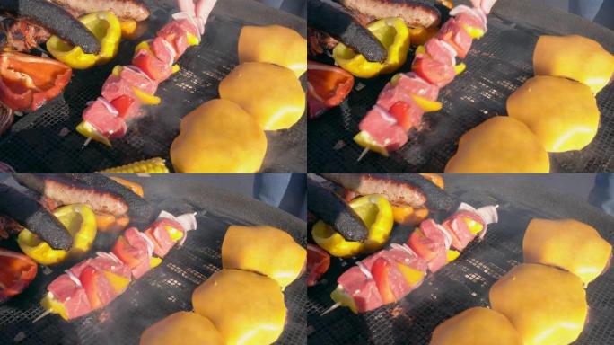 将洋葱和胡椒粉的牛排烤肉串放在烤架上，上面放着各种肉和蔬菜