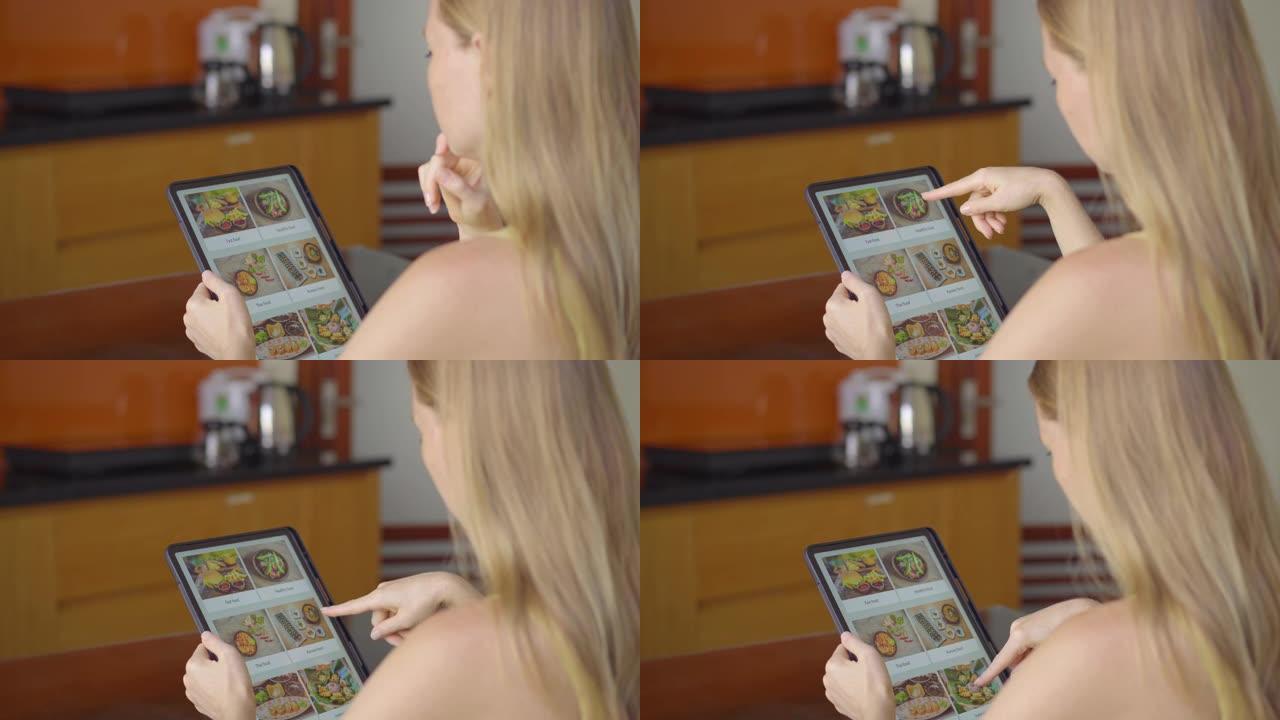 年轻女子用平板电脑在网上订购午餐食物。她坐在公寓的厨房里