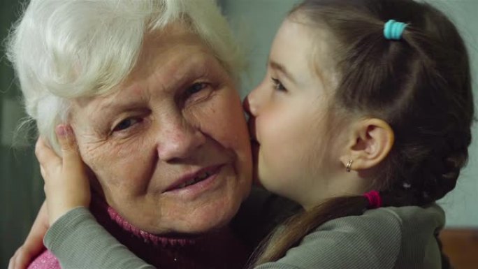可爱开朗的孙女多次亲吻她年迈的奶奶的脸颊。年轻女孩和老妇人在一起。两代人之间的温暖关系