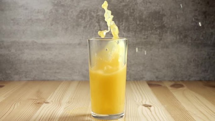 冰块掉入装有橙汁的玻璃杯中。慢动作