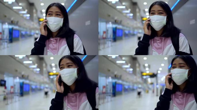 亚洲年轻女性戴防护口罩电话通话机场主厅、机场航站楼、病毒新型冠状病毒肺炎大流行的安全旅行之旅、新常态