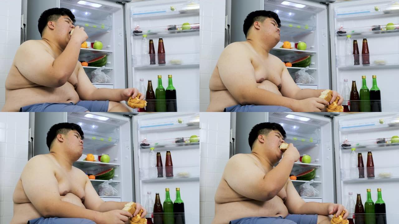 大身材的亚洲人吃冰箱里的面包。