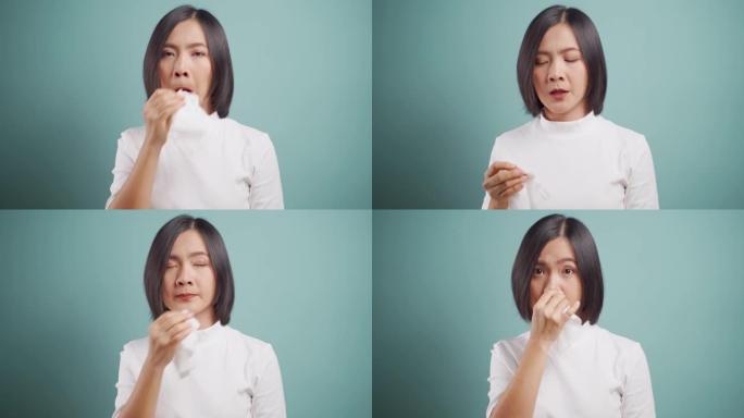 亚洲妇女因发热打喷嚏而生病，并被隔离在蓝色背景上的薄纸擦拭鼻涕。医疗保健概念。4k视频。