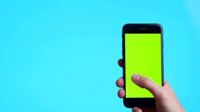 女人手拿着黑色智能手机，绿屏触摸或按下显示，男人使用手机，蓝底色键触摸显示