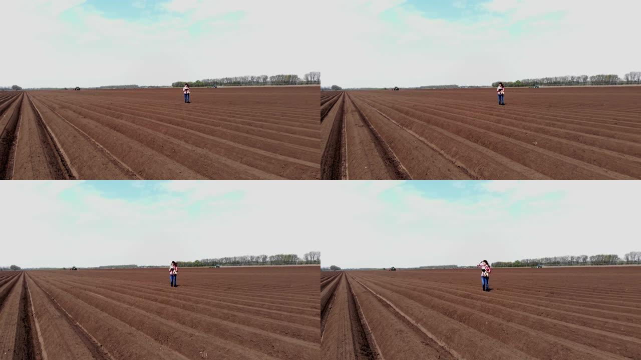航空。女农民、农学家以特殊的土壤行在田间。她用药片测试拖拉机自动种植土豆的质量。现代农业,农业。春天