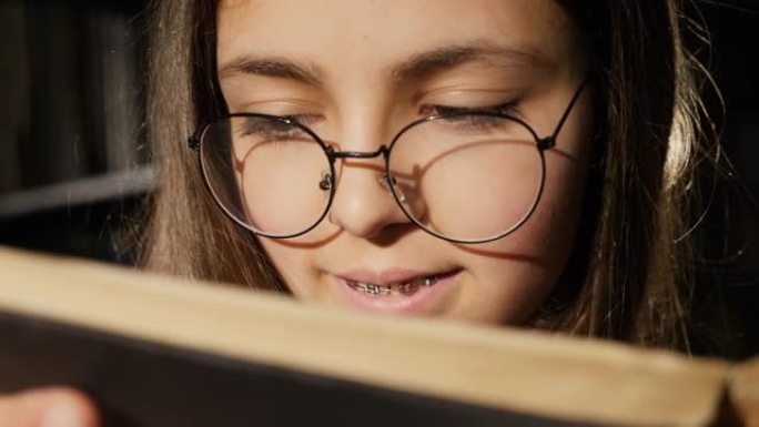 戴眼镜的女孩在图书馆看书，特写