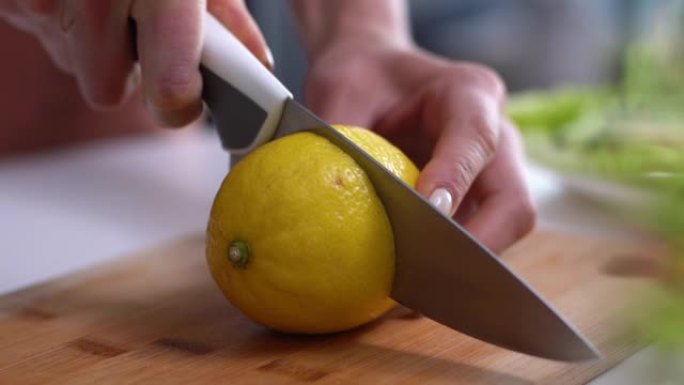 船上用菜刀切割新鲜柠檬的女人的手的特写。