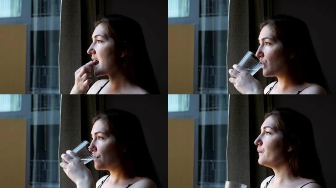 积极的女人在酒店房间服用药丸并喝水