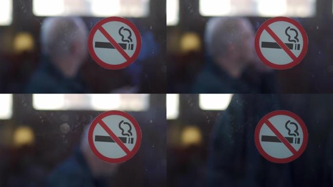 玻璃门上禁止吸烟标志，阳台上吸烟的人。