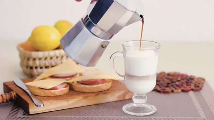 在家庭厨房中制作拿铁玛奇朵，将咖啡从莫卡壶倒入高杯和牛奶中