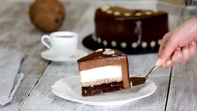 一块巧克力慕斯蛋糕，椰子馅在旧的木制背景上。镜面釉慕斯蛋糕。
