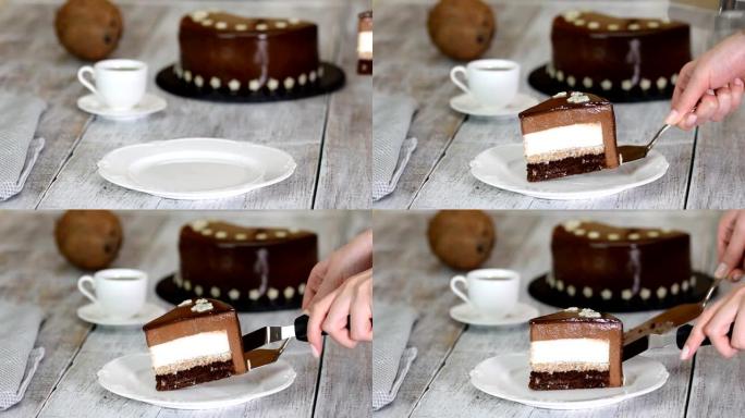 一块巧克力慕斯蛋糕，椰子馅在旧的木制背景上。镜面釉慕斯蛋糕。