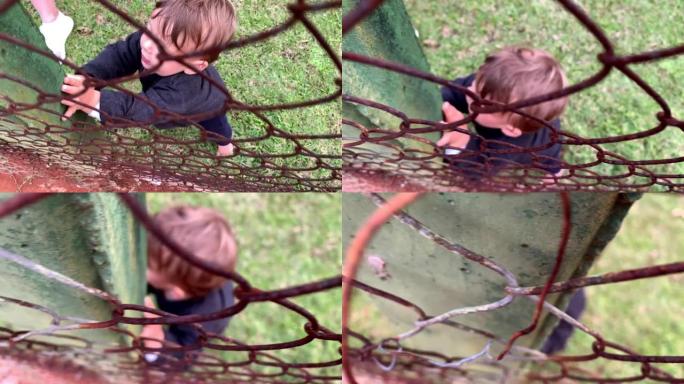 儿童婴儿通过靠在金属丝围栏上学习站立和行走