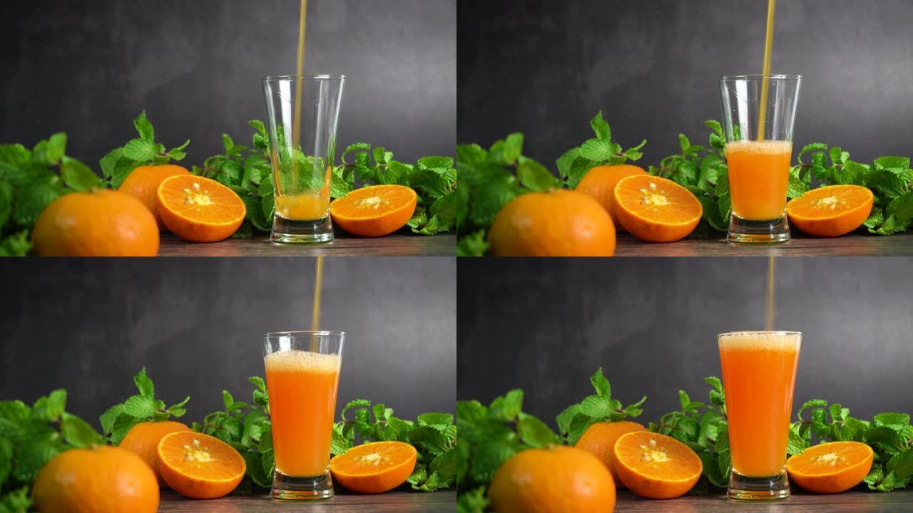 将新鲜的橙汁倒入带有橙子水果和薄荷的玻璃杯中，放在桌子上，健康食品中。
