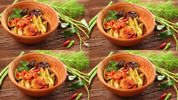Som Tam是受欢迎的泰国菜。芒果沙拉配干虾、咸蟹、辣椒、番茄和辛辣香草。配蔬菜。静静在工作室拍摄