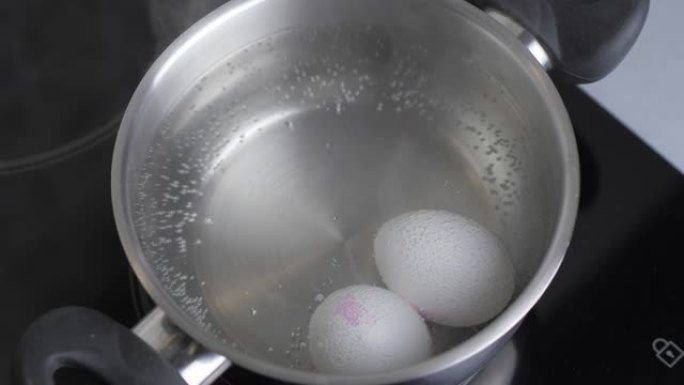 两个生白鸡蛋在不锈钢锅中煮沸，放在沸水中。健康的天然蛋白质早餐烹饪。鸡蛋煮沸了。热水鸡蛋。电影4k视