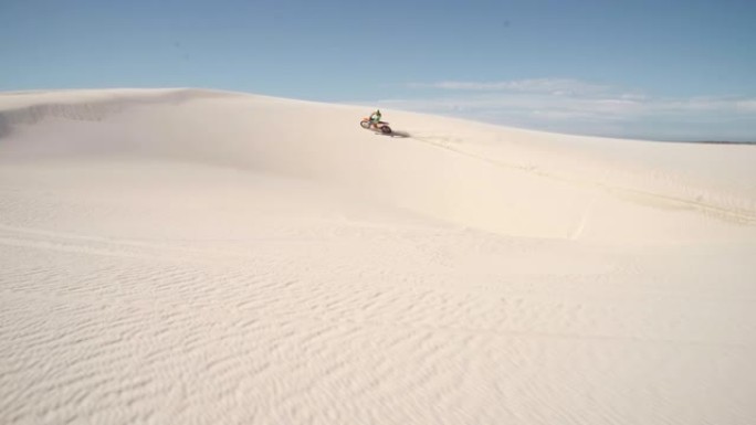 污垢骑自行车的人在沙丘上快速行驶
