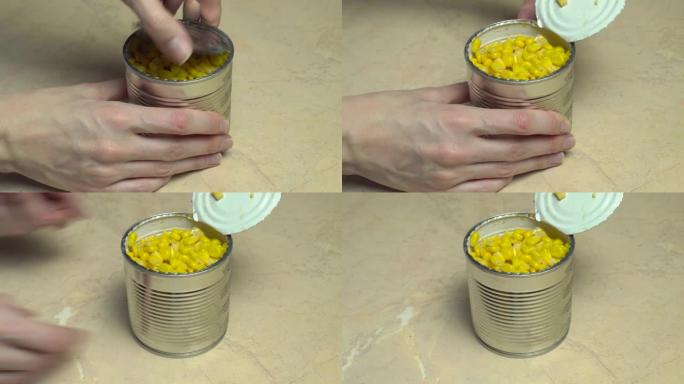 一只雌性的手打开一个罐装玉米的铁罐。