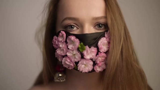 华丽的春姑娘，面具上有鲜花。我们无法呼吸的春天，花香。戴着花朵和花蕾面具的波特女孩。冠状病毒，口罩，