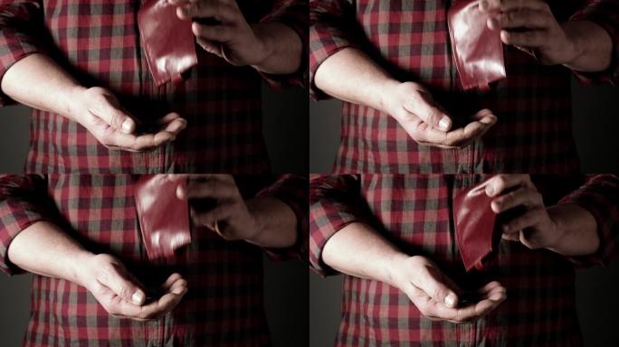 穿着红色衬衫的男人从棕色皮革钱包里倒格里夫纳硬币到他手里，贫穷概念到他手里