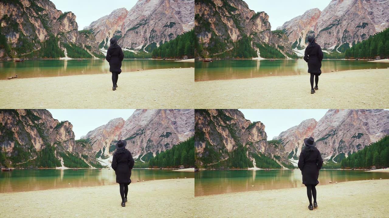 全黑向后看，神秘的女人转身沿着明亮的海岸走到迷人的布莱斯湖，迷人的意大利自然之美和多洛米蒂高山的绿色
