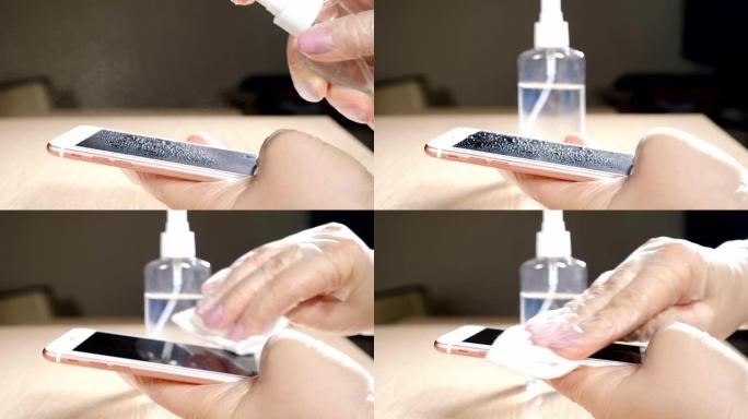 针对危险的电晕病毒和细菌的电话消毒。使用湿巾和消毒剂清洁手机屏幕的女性手在防护手套中的特写镜头。女性