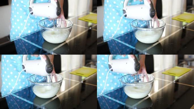 女厨师将蛋清与玻璃透明碗中的搅拌器混合成白色通风泡沫状态。