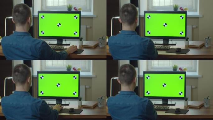男性视频编辑器可以在他的个人计算机上使用绿色大屏幕模拟显示。