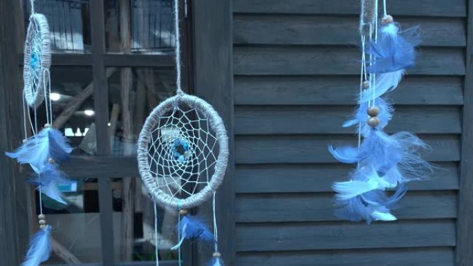 追梦者的蓝色羽毛悬挂在木屋前，缓慢移动，漂浮-传统的印度护身符