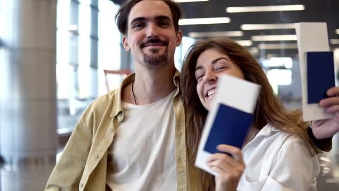 兴奋的高加索夫妇去度假的肖像。路过机场，拿着护照、登机牌。挥舞着办理登机手续的护照，对着镜头微笑，拥