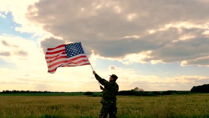 士兵侧身站着，高举美国国旗对抗蓝天。慢动作