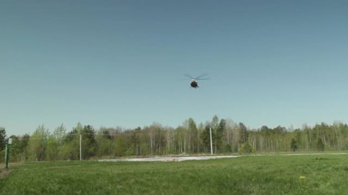 一架直升机从森林和田野的远处飞过。