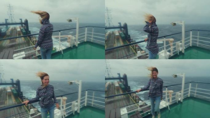 年轻女子在船上行走的剪影。站在大型运输货船的渡轮上。灰色多云的天空恶劣的天气风暴警告风暴暴雨飓风在海