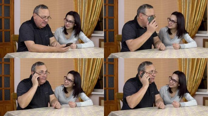 女儿教父亲如何使用电话。一名年轻女子向她的老父亲展示了在哪里点击智能手机。那个人打了电话。一家人坐在