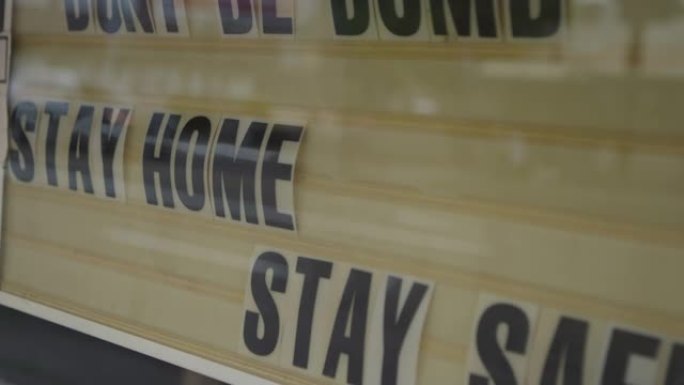 在商业窗口上签名，上面写着 “别傻。呆在家里。保持安全。” 在新型冠状病毒肺炎大流行期间