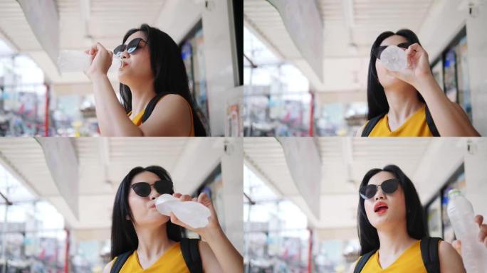 亚洲旅游女子在华欣市喝一瓶水，旅游
