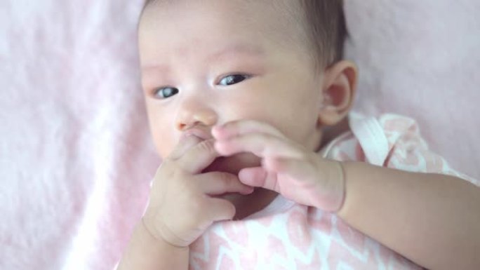 亚洲婴儿吮吸手指在床上创造幸福。