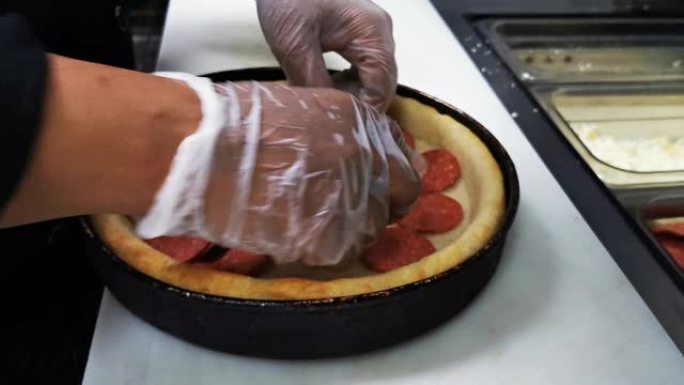 深盘披萨制作短片。放入意大利辣香肠并加入奶酪