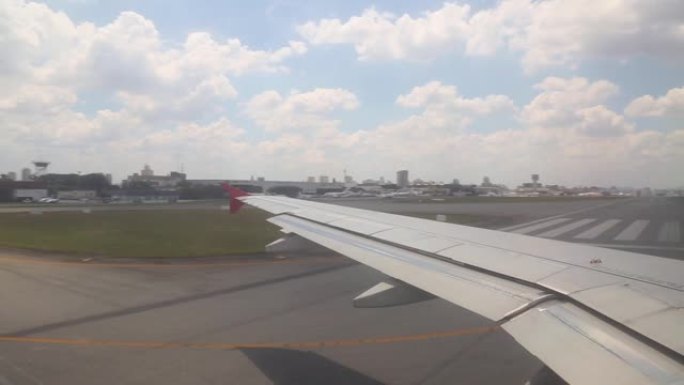 飞机在跑道上滑行，准备从窗户拍摄的机场背景中的蓝天和云彩起飞