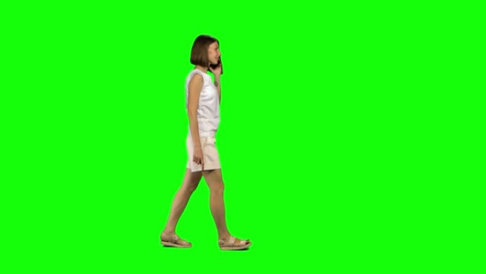 棕色光滑发型的年轻女子在绿屏上平静地在手机上行走和交谈。纵断面视图
