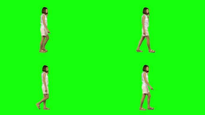 棕色光滑发型的年轻女子在绿屏上平静地在手机上行走和交谈。纵断面视图