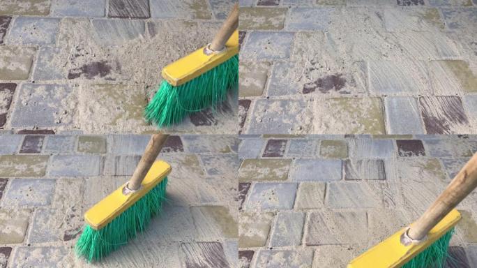 瓷砖人行道上用扫帚在接缝上摩擦沙子的过程