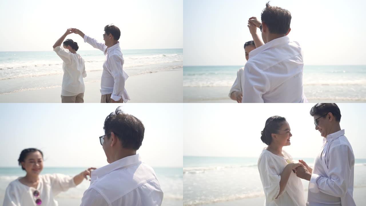 高清慢动作快乐的亚洲高级夫妇男人和女人手牵手，微笑着在海滩上跳舞。退休老年家庭在浪漫婚姻周年旅行中放