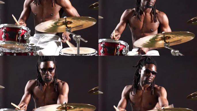 英俊的非洲鼓手带着辫子坐在鼓上，用棍子敲打