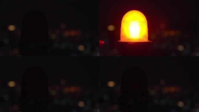 4k夜间在市区摩天大楼塔楼屋顶闪烁的橙色障碍物灯，背景模糊。在黑暗中闪烁警告或警告灯。