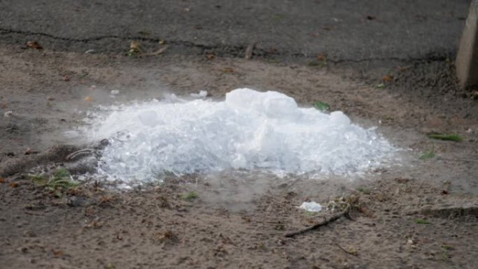 白色的冰块躺在棕色的地面上，并在春季蒸